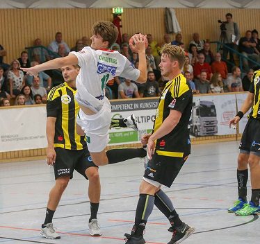 SCM-Youngster Robin Danneberg im weißen Trikot setzt im Sprungwurf zum Torwurf gegen zwei Verteidiger an.