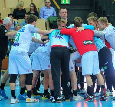 Handballspieler der SC Magdeburg Youngsters versammeln sich im Kreis zur Teambesprechung während einer Auszeit.