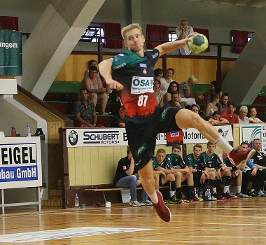 SCM-Youngster Richard Lößner im grünen Trikot setzt im hohen Sprungwurf zum Torwurf an.