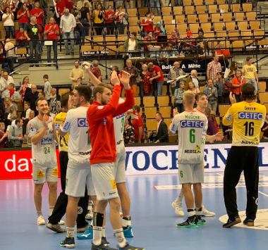 Handballspieler des SC Magdeburg klatschen nach dem Auswärtssieg gegen die Eulen Ludwigshafen auf dem Spielfeld ab.