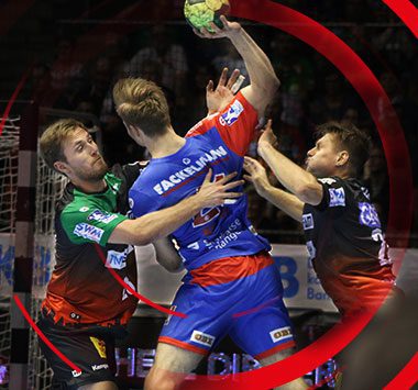 Handball-Actionaufnahme aus dem Spiel SC Magdeburg gegen HC Erlangen: Mehrere Spieler kämpfen um den Ball in der Luft, darunter ein Magdeburger in grünem Trikot und ein Erlanger in blau-rotem Trikot.