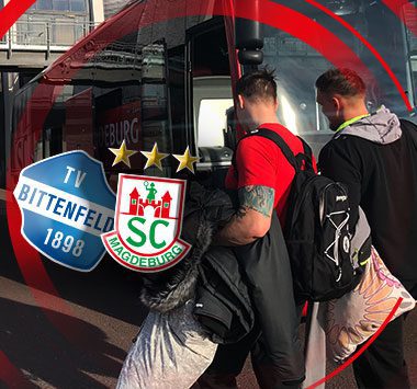 Zwei SC-Magdeburg-Spieler steigen in den Mannschaftsbus ein, daneben die Logos von TV Bietigheim und SC Magdeburg mit drei goldenen Sternen.