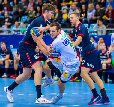 Rückraumspieler Christian O'Sullivan (Mitte) im weißen SCM-Trikot im Angriff, bedrängt von zwei Abwehrspielern der SG BBM Bietigheim.