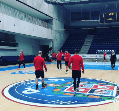 Spieler des SC Magdeburg in roten Trainingsshirts beim Aufwärmen in der heimischen Arena vor dem EHF-Cup-Spiel gegen Porto.