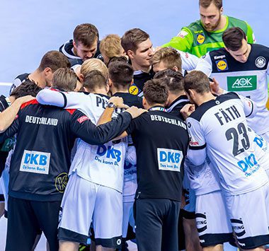 Die Spieler und Trainer der deutschen Nationalmannschaft versammeln sich während einer Auszeit im Spiel gegen Frankreich im Kreis auf dem Spielfeld.