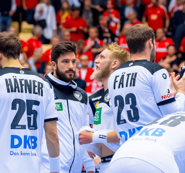 Spieler der deutschen Handballnationalmannschaft stehen während einer Spielunterbrechung gemeinsam auf dem Spielfeld.