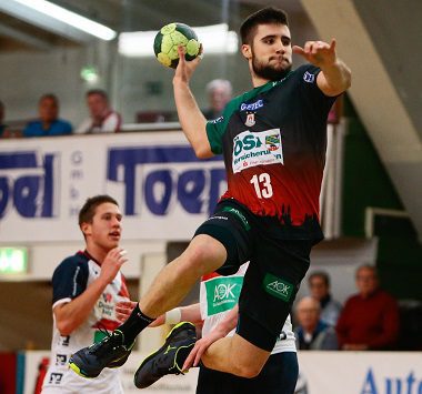 Handballspieler Juan de la Peña im grün-roten Trikot des SC Magdeburg beim dynamischen Sprungwurf während eines Spiels.
