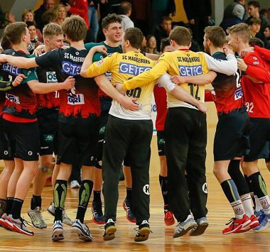 Die Handballspieler der SCM Youngsters liegen sich in einem großen Teamkreis jubelnd in den Armen.