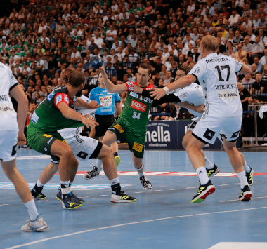 SCM-Handballspieler im grün-roten Trikot bricht im Angriffsspiel durch die Abwehr des THW Kiel durch.