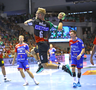 SCM-Handballspieler Matthias Musche setzt im dunkelgrünen Trikot in der Luft zu einem Sprungwurf an.