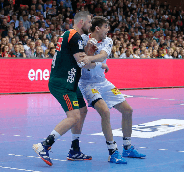 Dynamische Spielszene im Handball zwischen einem Spieler des SC Magdeburg und der TSV Hannover-Burgdorf.