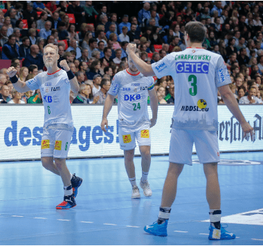Handballspieler des SC Magdeburg jubeln gemeinsam auf dem Spielfeld.