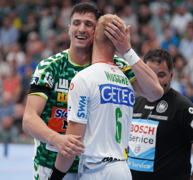 SC Magdeburg Handballer Matthias Musche (Nummer 6) umarmt versöhnend ein Spieler von Frisch Auf! Göppingen auf dem Spielfeld.