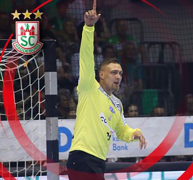 SC Magdeburg Torhüter Dario Quenstedt im gelben Trikot zeigt mit dem Zeigefinger nach oben.