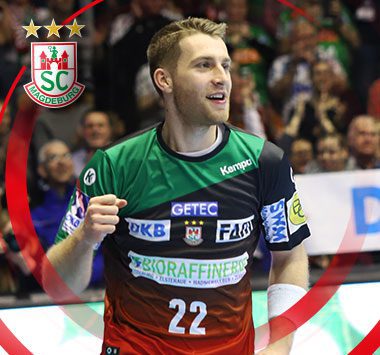SC Magdeburg Handballer Lukas Mertens (Nummer 22) jubelt lächelnd auf dem Spielfeld.
