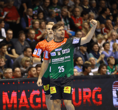 SC Magdeburg Handballer Marko Bezjak (Nummer 25) jubelt mit erhobenem Arm neben Matthias Musche auf dem Spielfeld.