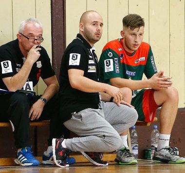 Blick auf die Auswechselbank der SCM Youngsters: Ein Trainer gibt einem Spieler in grün-roter Trainingskleidung im Sitzen taktische Anweisungen, während ein Betreuer daneben zuhört.