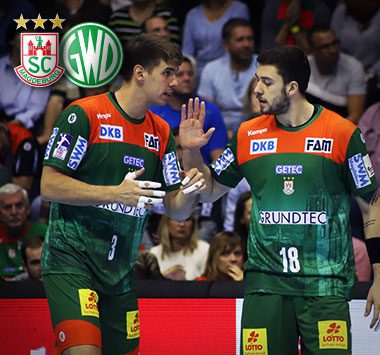 Die Handballspieler Albin Lagergren und Filip Kuzmanovski stehen im grün-roten Trikot des SC Magdeburg besprechend auf dem Spielfeld.