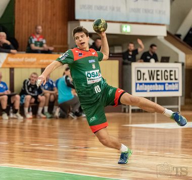 Ein Handballspieler des SC Magdeburg II springt im grün-roten Trikot (Nummer 10) frei vor dem Tor zum Wurf ab.