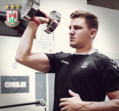 Krafttraining: Christoph Steinert (SC Magdeburg) drückt im schwarzen Trainingsshirt fokussiert eine Kurzhantel nach oben