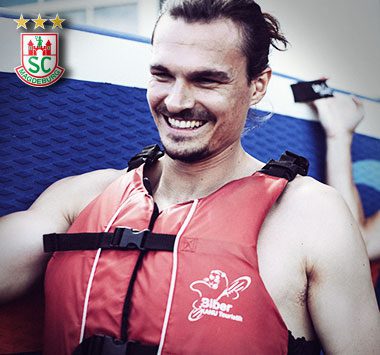 Teamevent: Jannick Green (SC Magdeburg) blickt mit einer roten Schwimmweste gut gelaunt und lachend nach rechts.