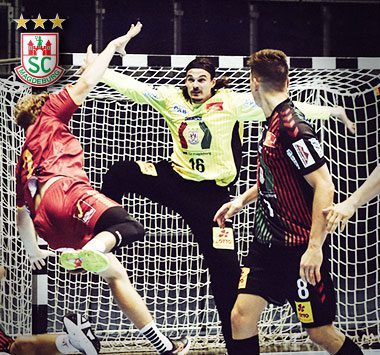 Spielszene beim Handball: SCM-Torwart Jannick Green (Nummer 16) pariert im gelben Trikot einen Sprungwurf des gegnerischen Angreifers im roten Trikot.
