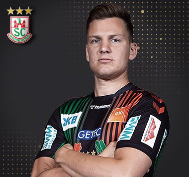 Spielerporträt: SCM-Rückraumspieler Christoph Steinert blickt im grün-schwarzen Trikot mit verschränkten Armen fokussiert nach vorne.