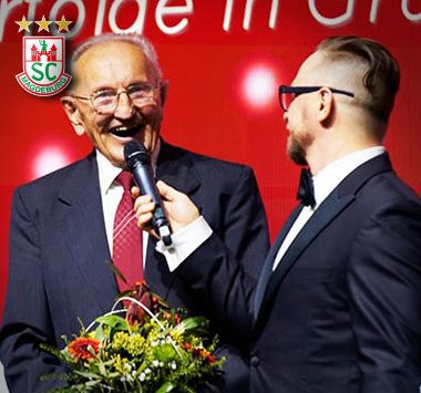 Geburtstags-Gedenkbild für Karl Schalditz bei einer Rede mit Mikrofon.