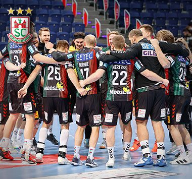 Die Handballmannschaft des SC Magdeburg jubelt gemeinsam im Kreis auf dem Spielfeld.