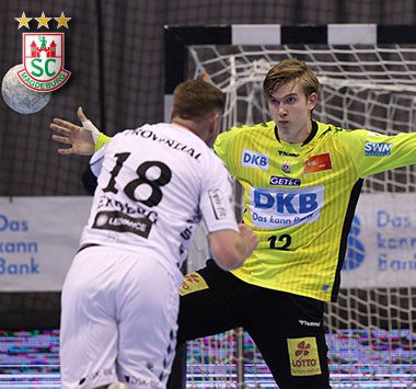 Torhüter Tobias Thulin in Abwehrposition im Tor des SC Magdeburg, beobachtet von einem Gegenspieler mit der Rückennummer 18.