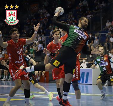 Željko Musa (Nummer 2) bricht im grün-roten SCM-Trikot am Kreis durch und setzt im Sprungwurf zum Torwurf an.