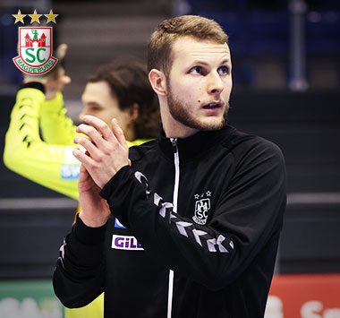 Justus Kluge steht in einer schwarzen Aufwärmjacke am Spielfeldrand und klatscht Beifall.