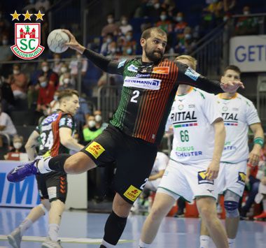 Željko Musa (Nummer 2) bricht im grün-roten SCM-Trikot am Kreis durch und setzt im Sprungwurf zum Torwurf an.