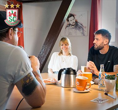 Bennet Wiegert sitzt mit zwei weiteren Personen an einem Tisch bei der Aufzeichnung des Magde-Podcasts.