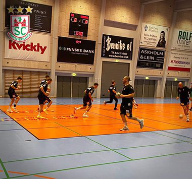 SCM-Spieler laufen sich in schwarzen Trainingsshirts auf dem orangefarbenen Hallenboden für ein Testspiel in Dänemark warm.