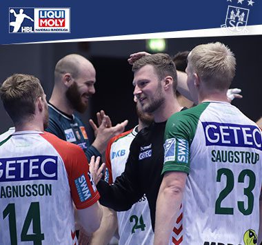 Spieler des SC Magdeburg klatschen lächelnd auf dem Spielfeld miteinander ab.
