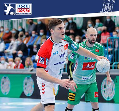 Kay Smits läuft im grün-weißen Trikot des SC Magdeburg mit dem Handball in der Hand an einem Abwehrspieler vorbei.