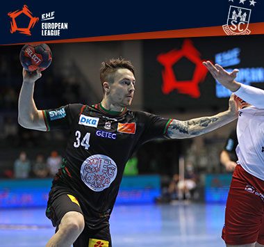 Michael Damgaard blickt im schwarzen Trikot des SC Magdeburg mit dem Handball in der Hand fokussiert nach vorne.