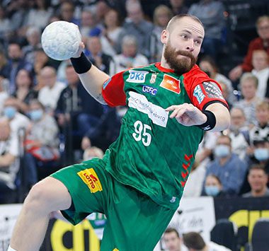 Moritz Preuss springt im grün-roten Trikot des SC Magdeburg zum Torwurf.