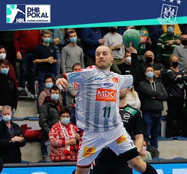 Daniel Pettersson holt im grau-weiß gestreiften Trikot des SC Magdeburg zum Sprungwurf aus.