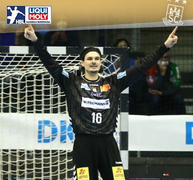 Torhüter Jannick Green jubelt im schwarzen Trikot des SC Magdeburg mit erhobenen Armen vor dem Tor.