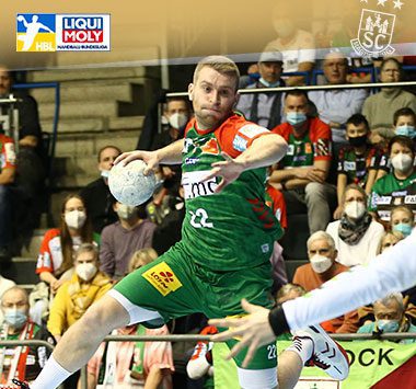 Lukas Mertens fliegt im grün-roten Trikot des SC Magdeburg im Sprungwurf zum Tor.