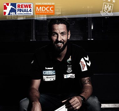 Cheftrainer Bennet Wiegert lächelt in schwarzer Kleidung während eines Interviews.