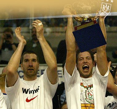 Zwei Handballer des SC Magdeburg jubeln ausgelassen und recken den Champions-League-Pokal in die Höhe.