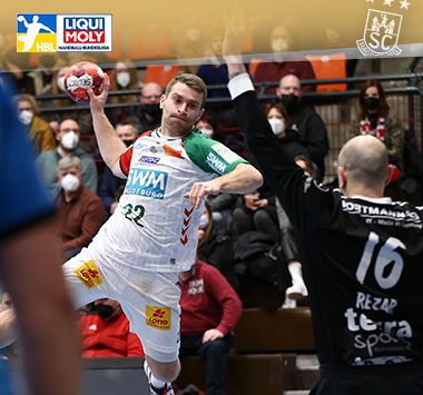 Lukas Mertens zieht im weißen Trikot des SC Magdeburg im Sprungwurf ab.