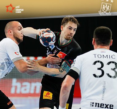 Michael Damgaard setzt sich im schwarzen Trikot des SC Magdeburg gegen zwei Abwehrspieler durch.