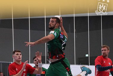 Ein Spieler des SC Magdeburg holt im grün-roten Trikot im Sprungwurf zum Torwurf aus.