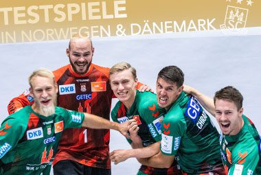 Die Spieler des SC Magdeburg jubeln gemeinsam auf einer Ankündigungsgrafik für Testspiele.