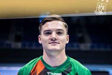 Kay Smits blickt im grün-roten Trikot des SC Magdeburg lächelnd nach vorne.