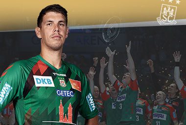 Porträt von Handballspieler Piotr Chrapkowski im grünen SCM-Trikot vor einer jubelnden Fankulisse.